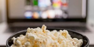 A bowl of popcorn in front of a TV screen