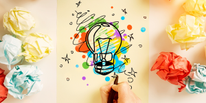 Pen sketched light bulb surrounded by colorful doodles and paper.